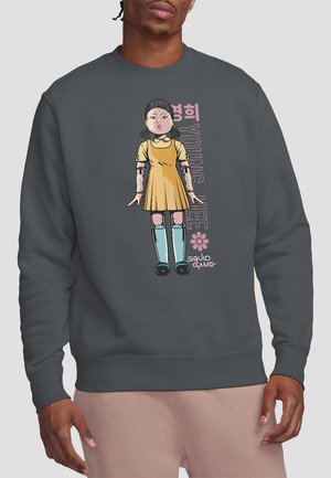 Dark gray sweatshirt featuring a cartoon character in a yellow dress and turquoise socks, with "YOUNG HEE" text and a pink flower design.