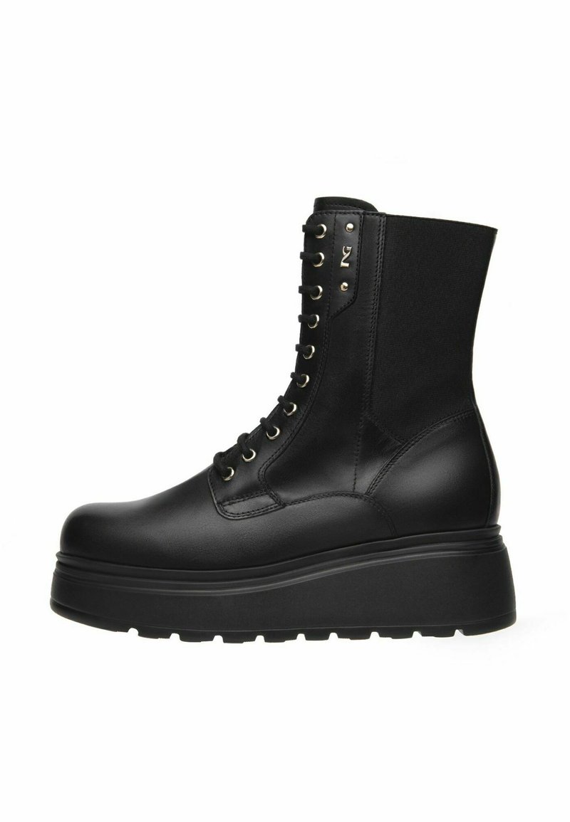 Stivale da combattimento in pelle nera con plateau, lacci frontali, suola spessa e pannello elastico nella parte superiore sul retro.