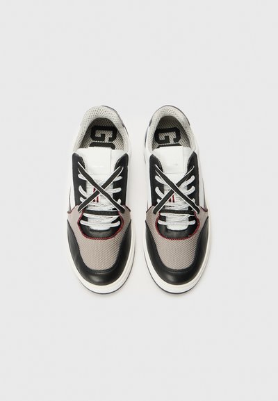 Scarpe sportive con tomaia in rete nera e grigia, accenti bianchi, lacci prominenti e punta rotonda. Cuciture rosse delineano il design.