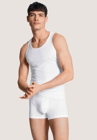 Witte tanktop met een geribbelde textuur en bijpassende boxershorts, beide met een eenvoudig ontwerp en een strakke pasvorm. Effen achtergrond.