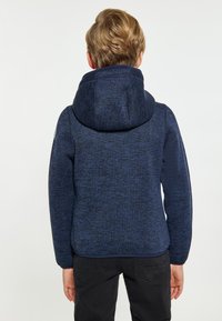 Tamsiai mėlynas fliso džemperis su dideliu gobtuvu, tekstūruotu audiniu ir prigludusia forma, ilgas rankoves ir tiesus apdaila, tinkamas kasdieniam dėvėjimui.