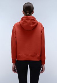 Rode hoodie met een grote capuchon, geribbelde manchetten en onderrand. Stof met een gladde textuur, korte snit, gezien vanuit de achterkant, gedragen met zwarte broek.