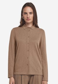 Brun långärmad skjorta med krage och knappstängning, tillverkad av texturerad tyg. Har en rak nederkant och slim fit.