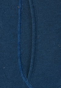 Tejido azul marino con una textura suave, que presenta una costura lateral y un cosido en contraste. El diseño es sencillo, sin patrones ni herrajes visibles.