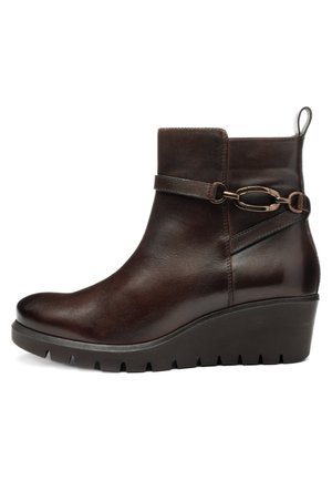 Donkerbruine leren enkellaars met sleehakzool, decoratieve riem, metalen kettinkdetail en trekhaak aan de achterkant.