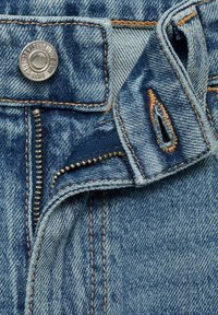 Denim jeans in light blue wash with visible stitching, zip fly, and metal button closure, showing texture and fabric detail.