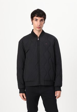 Black quilted bomber jacket with a stand collar, featuring a zip closure, ribbed cuffs, and a small logo detail on the chest.