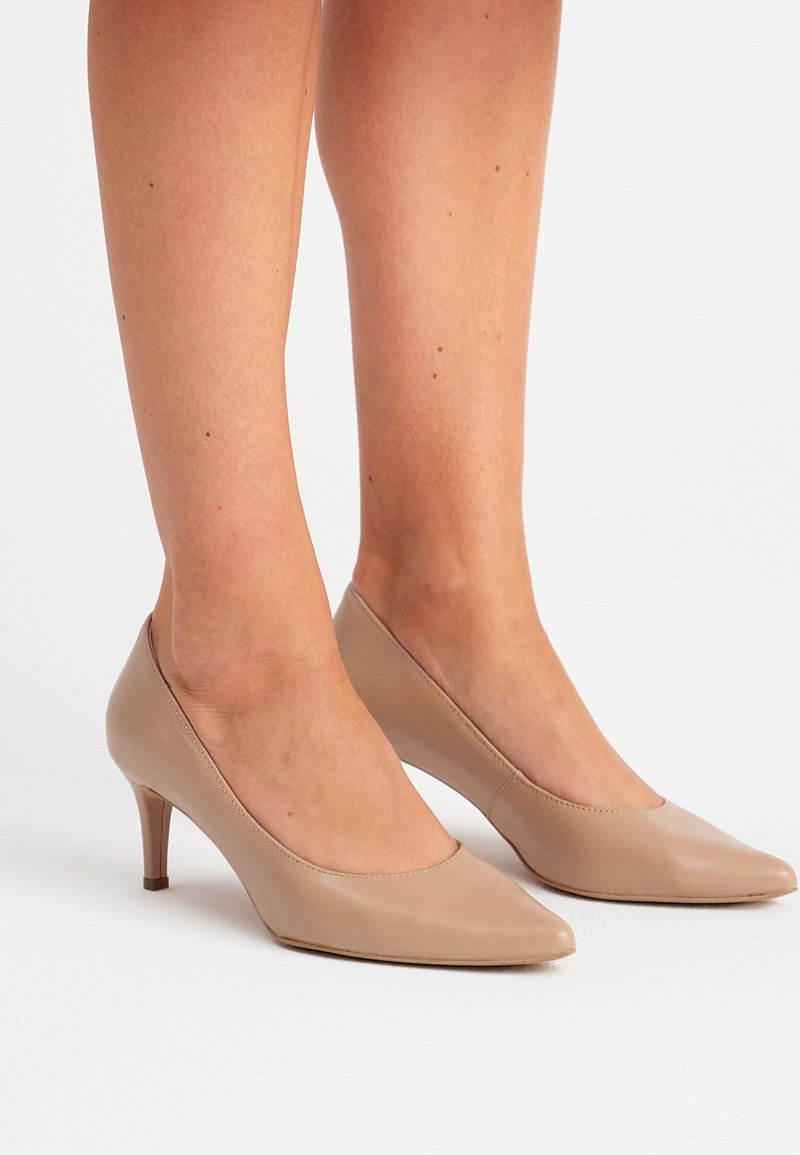Scarpe con tacco alto in pelle beige, con punta affusolata, texture liscia e sottile tacco di 5 cm. Design minimalista senza hardware visibile.