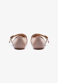 Due paia di scarpe flat in suede rosa con cinturini posteriori, caratterizzate da una texture liscia e un design minimalista. Inclusi dettagli in hardware dorato.