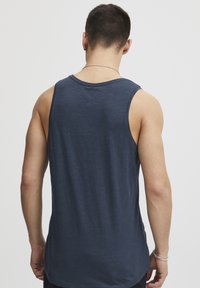 Maiou fără mâneci de culoare bleumarin, cu o croială lejeră, având un gât rotund și o textură moale, prezentând un design uniform pentru spate și umeri.