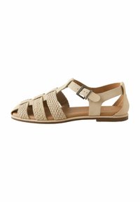 Woven leather sandal in beige with an open toe, adjustable ankle strap, and flat sole. Features cross-straps for ventilation and style.