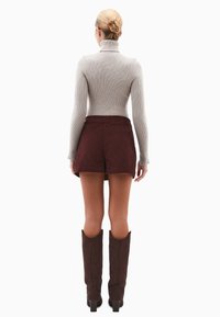 Szary prążkowany sweter z golfem, bordowe szorty z korduroyu i brązowe wysokie buty, pokazane z tyłu na białym tle.