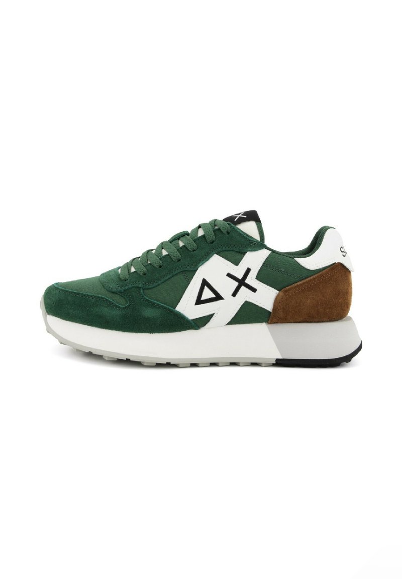 Las zapatillas de ante verde presentan una franja diagonal blanca y detalles en negro, con un panel trasero marrón y una suela blanca gruesa.