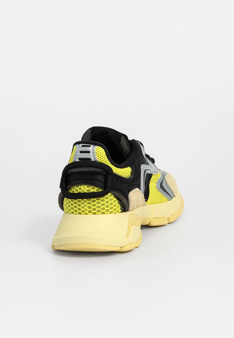 Baskets de sport avec un dessus en mesh noir, des accents jaunes et des superpositions texturées beiges. Semelle jaune rembourrée et languette de talon renforcée.