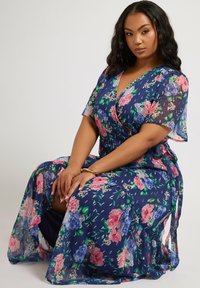 Un abito avvolgente navy a fiori realizzato in tessuto leggero, caratterizzato da motivi floreali rosa e blu, maniche corte e una fessura laterale.
