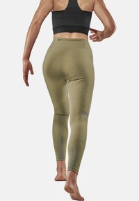 Olive green leggings with a textured diamond pattern, high waistband, and reflective accents on calf areas, designed for athletic wear.
