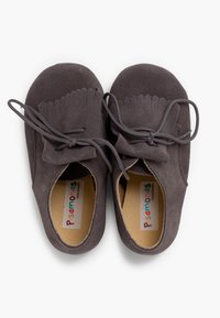 Zapatos de ante grises con punta redondeada y acentos con flecos. Disponen de cordones grises y una plantilla acolchada con una etiqueta de marca colorida.