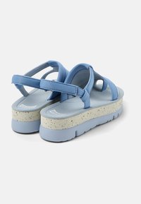 Blue platform sandals with crisscross straps and textured soles. Soft material with a speckled, lightweight base and padded insoles.