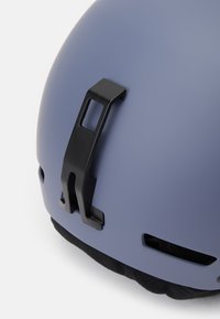 Modrý matný helma s černou sponou a ventilačními otvory. Viditelná měkká vnitřní výstelka. Hladký povrch. Vhodné pro ochranné použití.