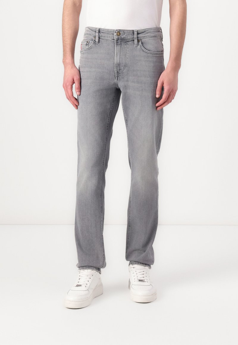 Pilkas džinsų audinio kelnes su tiesia siluetu, vidutinio aukščio liemeniu, klasikine penkių kišenių konstrukcija, subtiliu išblukimu ir mygtukų uždarymu.