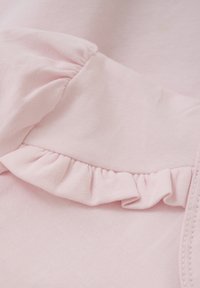 Ljusrosa bomullstyg med en texturerad yta, med en ruggad detalj längs sömmen för extra detalj.