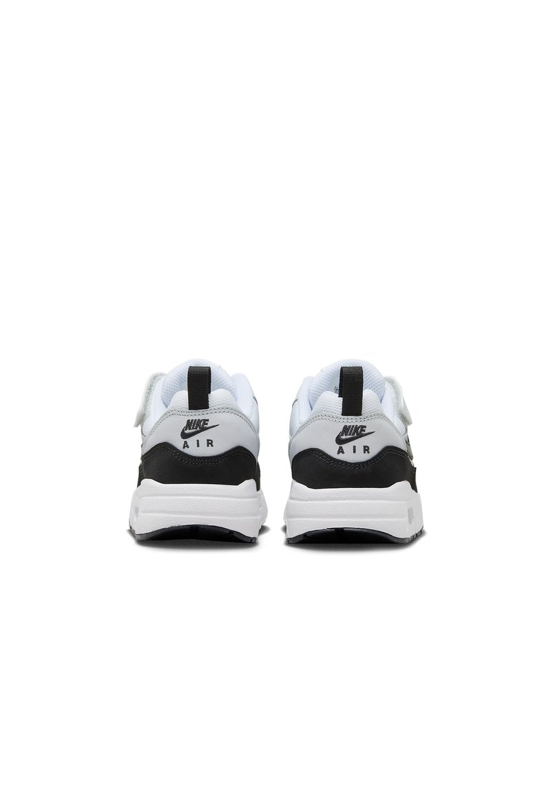 Witte en zwarte Nike-sneakers hebben een gladde leren bovenkant, een gevoerde kraag en opvallende branding op de hak en zijkant. Rubberen zool.