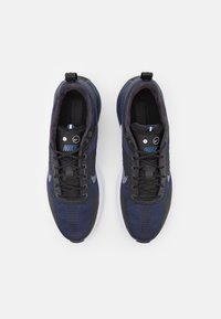 Nike sportcipő sötét navy hálós anyagból, texturált fekete részletekkel. Fűzős kialakítás, párnázott bokarész és fehér gumitalp jellemzi.