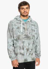 Svetlo šedý mikina s kapucňou s tie-dye motívom, s predným zipsovým uzatváraním, šnúrkami a náprsní kraťasou s diskrétnym logom. Mäkka textúra látky.