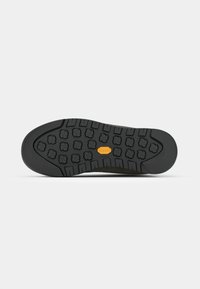 Svart gummisåle med teksturert mønster for godt grep, med Vibram-logo i oransje og en buet hælkant.