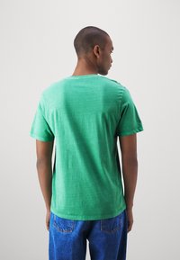Groene katoen t-shirt met een relaxte pasvorm, korte mouwen en een ronde halslijn. Heeft een licht gestructureerd oppervlak. Achteraanzicht weergegeven.