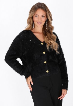 Cardigan negru, pufos, cu decolteu în V, butoane aurii în formă de floare și mici strasuri pe un umăr. Mâneci lungi și textură moale.