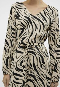 Langdurige jurk met lange mouwen en een V-hals, voorzien van een zwart en beige zebra-strepenpatroon, een gestructureerde stof en een strikdetail in de taille.