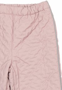 Lyserødt polstret stof med små hvide broderede prikker og en elastisk linning, der viser en del af et beklædningsstykke.