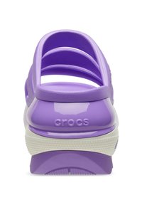 Crocs viola con una finitura lucida, caratterizzati da più strap orizzontali e una suola bianca. Il retro mostra il logo "crocs".