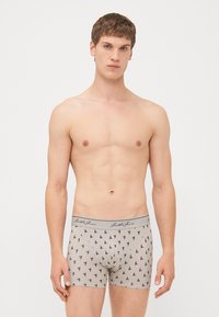 Graue Sportunterwäsche mit einem sich wiederholenden schwarzen Segelbootmuster, weichem Baumwollmaterial und einem grauen Bundesbund mit Logo-Details.