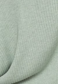 Lichtgroene ribfabric, getextureerd met verticale lijnen. De stof lijkt zacht en rekbaar, geschikt voor comfortabele draagbaarheid.