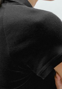 Czarna bawełniana koszulka z krótkim rękawem, charakteryzująca się gładką fakturą i okrągłym dekoltem. Starannie wykonane przeszycia wzdłuż krawędzi.