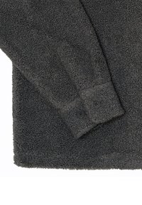 Manche de veste à texture duveteuse gris foncé avec deux boutons noirs sur le poignet sur fond blanc.