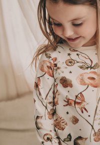 Langærmet skjorte i blødt cremefarvet stof med blomster- og dyremønstre i jordfarver, med accenter af mørkegrøn og subtile stjerner.