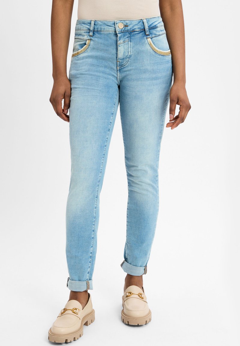 Lichtblauwe skinny jeans met gouden details op de zakken, omgeslagen zoom en lichte vervaging. Gepaard met beige platform instappers.