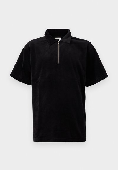 Polo noir en matériau doux et pelucheux, avec une courte fermeture éclair, coupe décontractée et manches courtes avec un col classique.