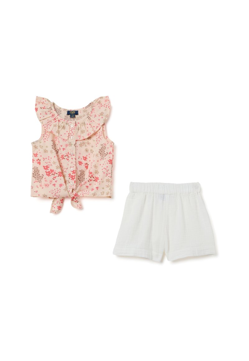 Bloemdruk zonder mouwen top met een ruches halslijn en strik voorkant; gecombineerd met witte, lichte shorts met een elastische tailleband.