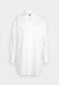 Chemise blanche à manches longues avec boutons, col pointu et poignets, étiquette « BOSS » à l'intérieur du col.