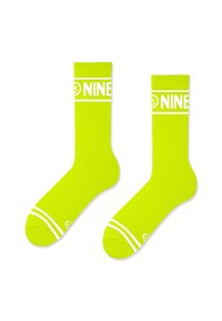 Neon żółte skarpetki do kolan z białym logo "NINE", prążkowana tekstura i dwa białe paski na środku stopy dla efektu wizualnego.