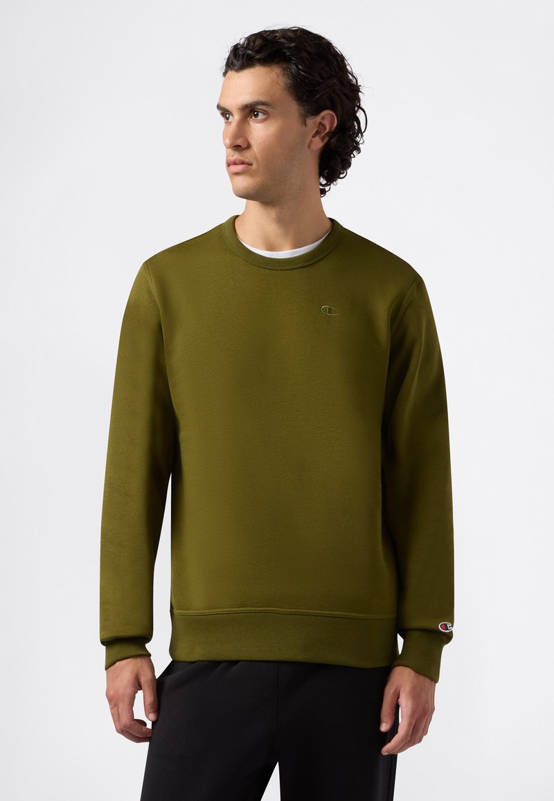 Oliwkowy sweter z miękkiego materiału, z okrągłym dekoltem, długimi rękawami, ściągaczami przy mankietach oraz małym logo na piersi.