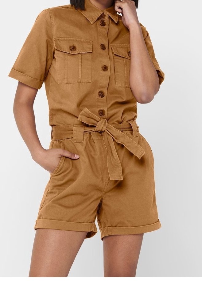 Combinaison courte en coton marron à manches courtes avec fermeture boutonnée sur le devant, deux poches poitrine, ceinture à la taille et shorts retroussés. Texture lisse.
