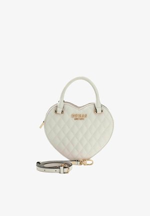 Herzförmige Handtasche aus weißem, gestepptem Kunstleder, mit goldfarbenen Beschlägen und verstellbarem Riemen. Auf der Vorderseite prangt das Logo "GUESS EST 1981".