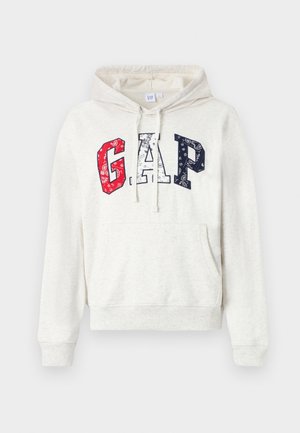 Kremfarget hettegenser med kengurulomme. Har "GAP"-logo i røde, hvite og blå mønstrede bokstaver. Laget av bomull, med snor til hetten.