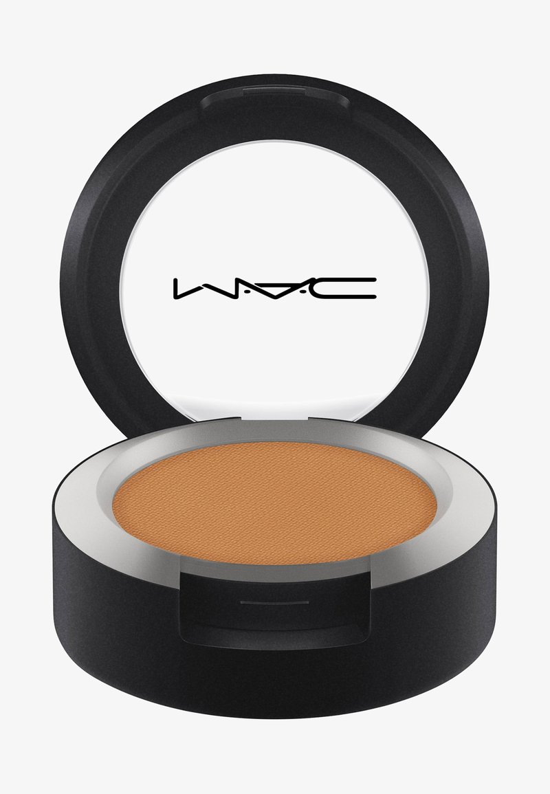 Okrągłe kompaktowe lusterko o czarnej obudowie i srebrnej obręczy, zawierające gładki, matowy proszek w średnim odcieniu brązu. Nazwa marki widoczna na pokrywce.