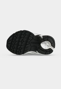 Μαύρη και άσπρη σόλα παπουτσιού New Balance για τρέξιμο με υφή στο πέλμα για καλύτερο κράτημα και ορατό λογότυπο της μάρκας στο κέντρο.